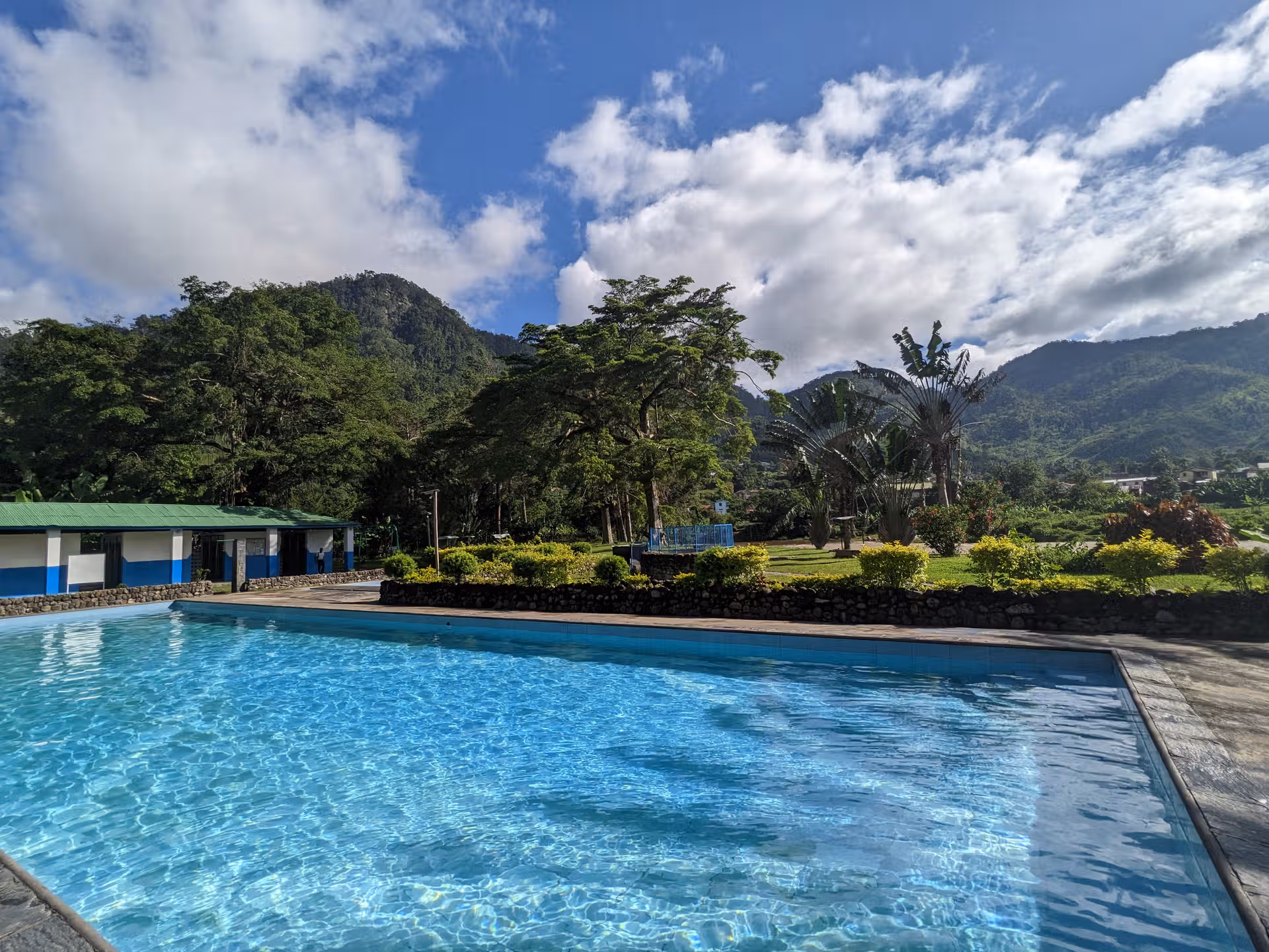 An image illustrating the natural thermal swimmingpool in Ranomafana with warm blue translucent water and green rainforest mountainous background