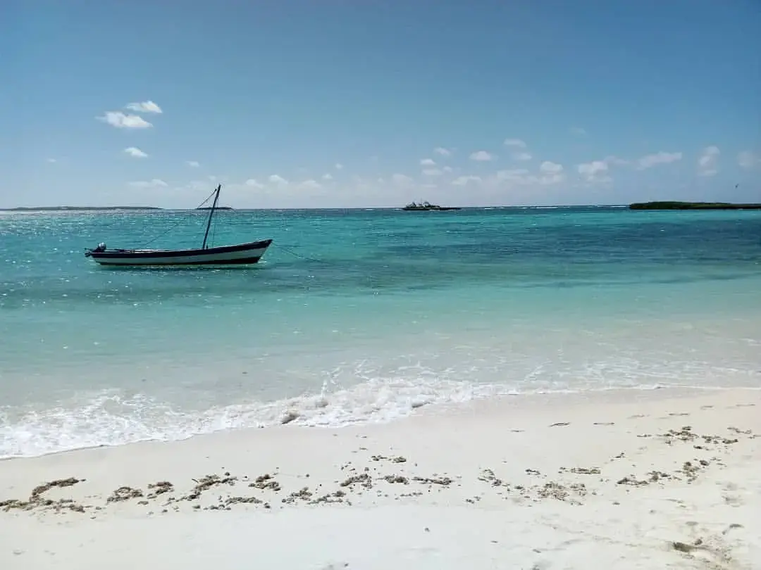 An image showing off a white sand beaches with a traditional pirogue above the blue and emerald sea water in Mer d'Emeraude Antsiranana Madagascar